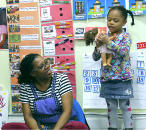 A play leader helps a young girl through play therapy