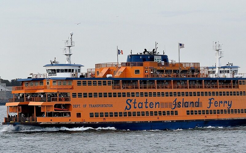 A Staten Island ferry crosses the bay on the backdrop of New York City where the NYU Adaptive Leadership Lab promotes human services leadership, with the Statue of Liberty in the background